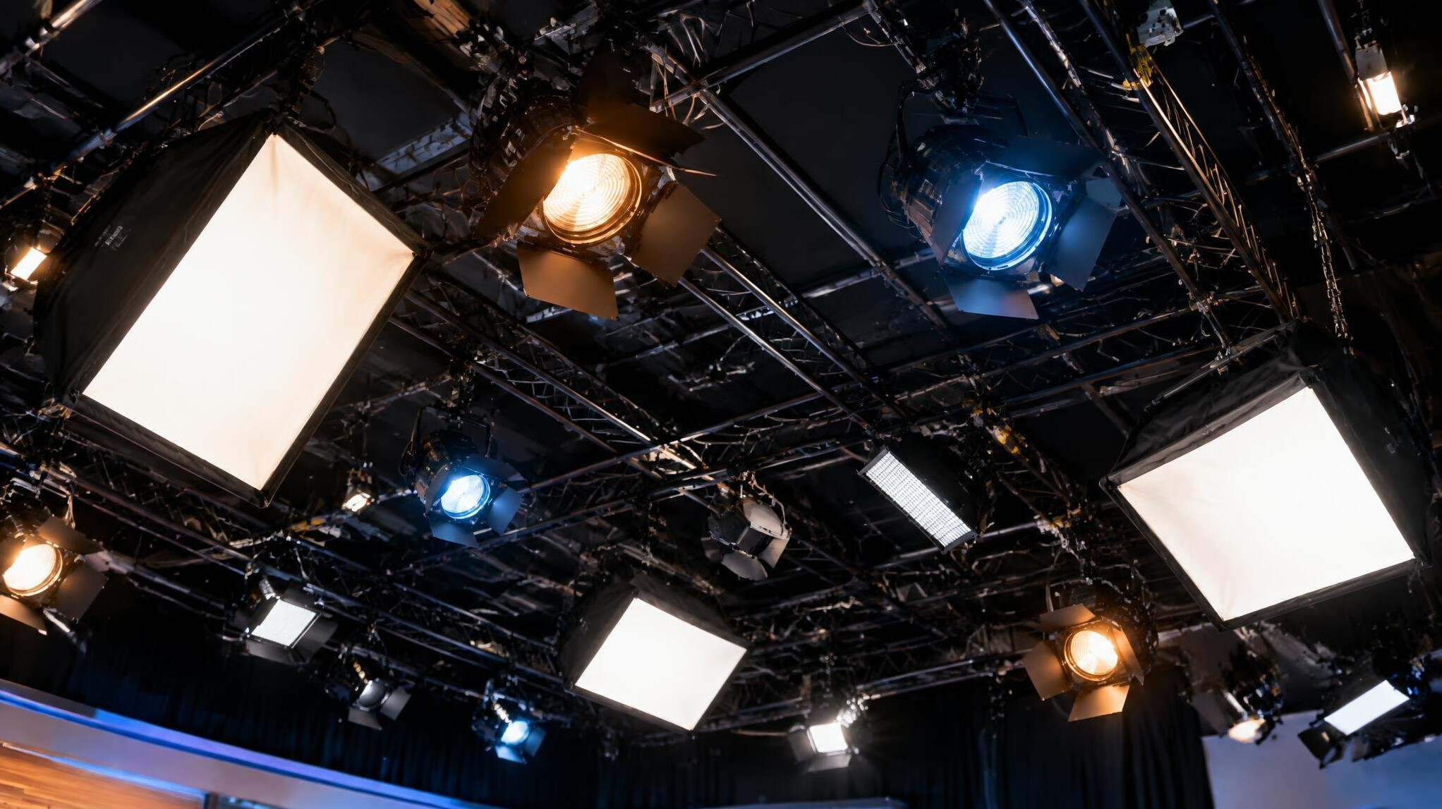 Overhead lighting grid with softbox and Fresnel fixtures above a news set
